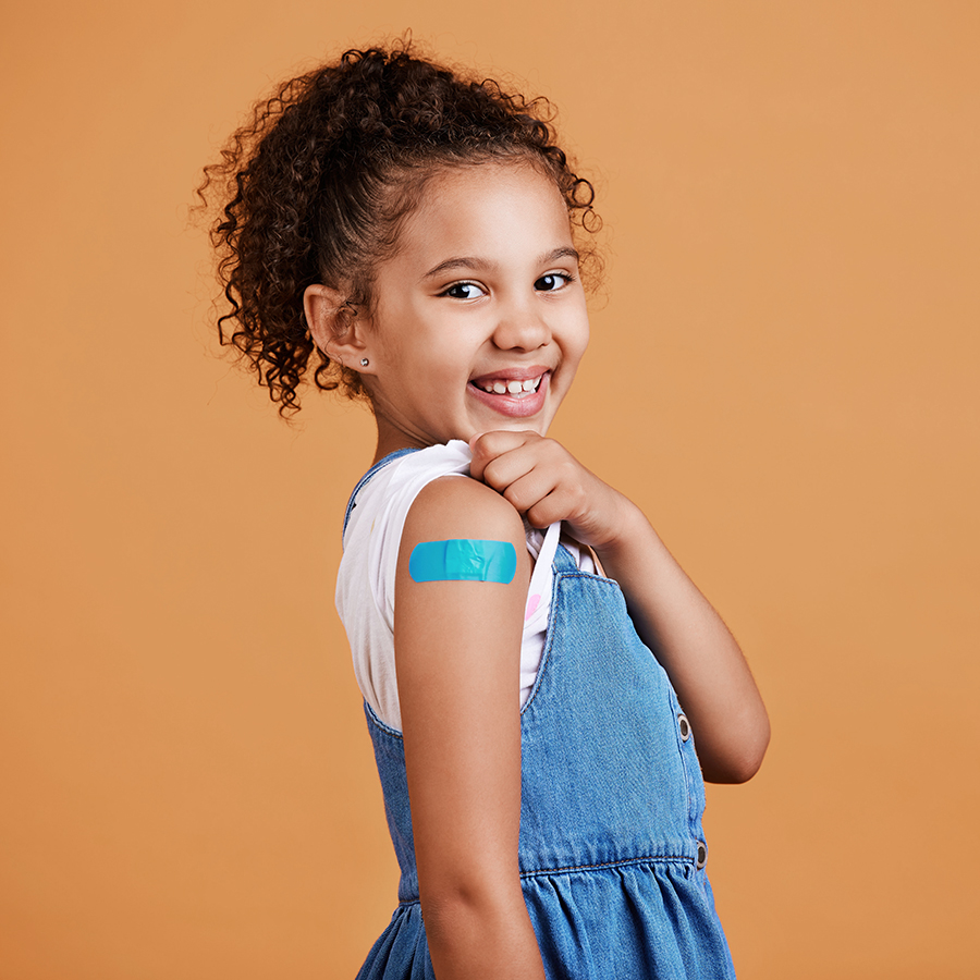Portrait plaster and girl with smile, confidence and vaccination against a studio background. Face, Latino female child and happy young person showing injection, happiness and cheerful on backdrop.